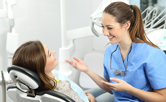 Smiling female dentist talking to female patient in chair