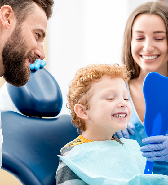 Dentist and parent showing child smile in mirror