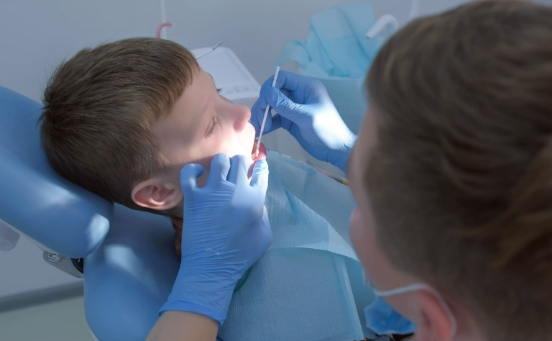 Little boy receiving fluoride treatment from dentist's office