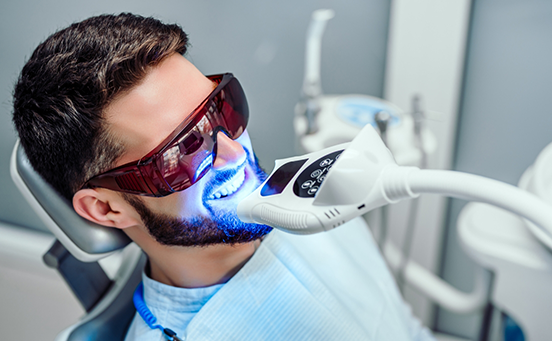 Man in dental chair receiving teeth whitening