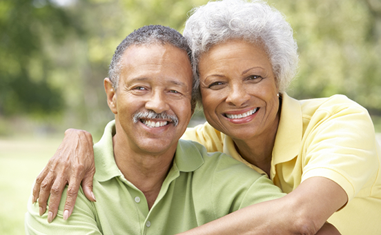 Senior man and woman sitting outside and smiling