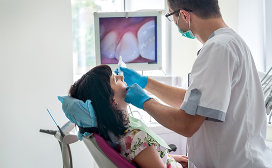 Dentist examining female patient's teeth with intraoral camera