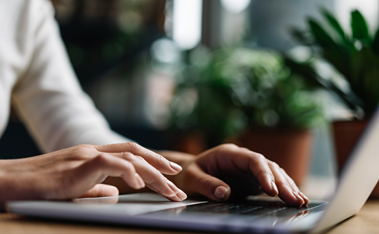 Typing on laptop on wooden table