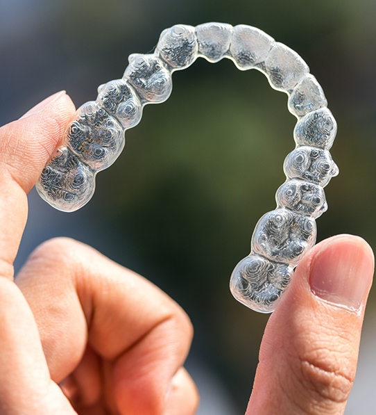 Close-up of hand holding a clear aligner