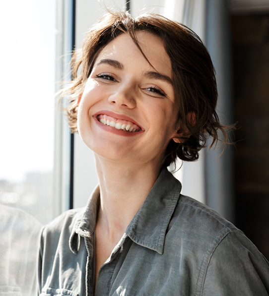 Woman standing next to window and smiling