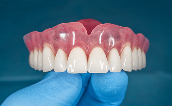 Close-up of gloved hand holding dentures