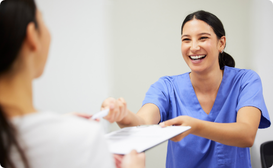 Smiling dentist handing patient a clipboard and pen