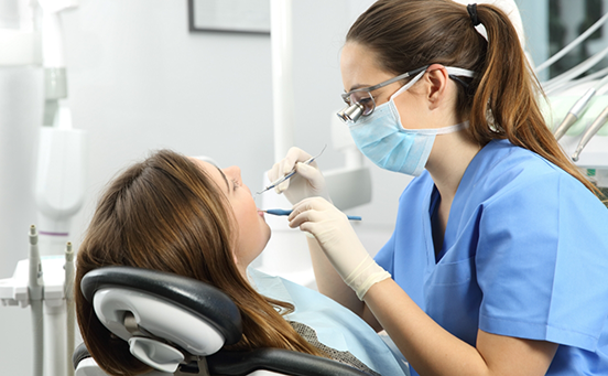 Female dental patient having teeth examined by dentist