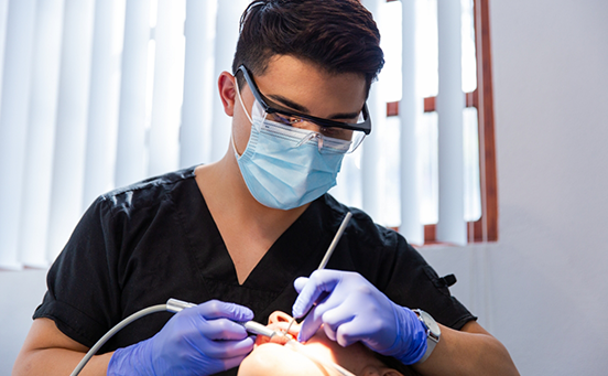 Male dentist performing oral cancer screening on patient