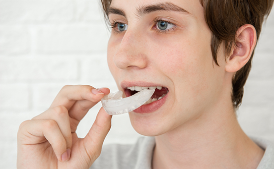 Boy taking out nightguard for bruxism