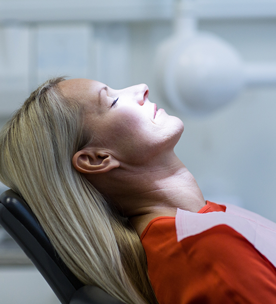 Woman relaxing in dental chair with eyes closed